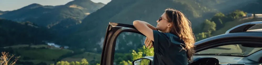 Woman traveling by car taking a moment to look at the mountains